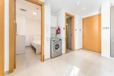 a laundry room with a washer and dryer at Balcony Offering Community Views 1BR with Assistant Room, Walking Distance to Community Park , Pantheon Elysee , Jumeirah Village Circle by Deluxe Holiday Homes in Dubai