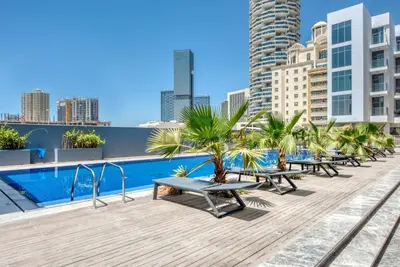 a pool on the roof of a building with benches at Balcony Offering Community Views 1BR with Assistant Room, Walking Distance to Community Park , Pantheon Elysee , Jumeirah Village Circle by Deluxe Holiday Homes in Dubai