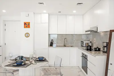 a kitchen with white cabinets and a table and chairs at Premium 1BR with Iconic Skyline Views with Balcony & Pool in Dubai