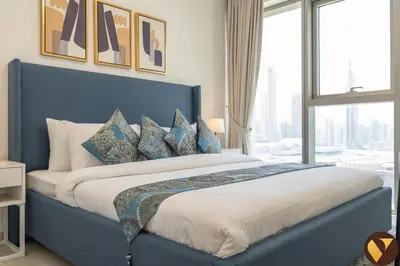 a bedroom with a blue bed with a large window at Vogue Downtown Views II with Direct Access to Dubai Mall Via a Climate Controlled Bridge, Two Bedroom Apartment with Balcony and Burj Khalifa View in Dubai