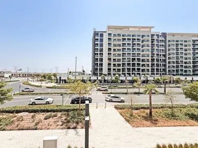 a parking lot with cars parked in front of a large building at Prime Studio Apt at Azizi Riviera 45, Meydan in Dubai