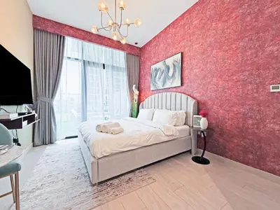 a bedroom with a red wall with a bed and a tv at Prime Studio Apt at Azizi Riviera 45, Meydan in Dubai