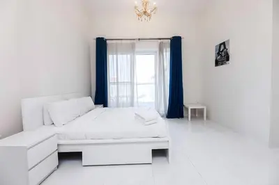 a white bedroom with a bed and a window at MK Residence JVC in Dubai