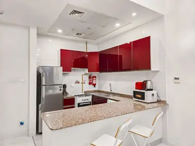 a kitchen with red cabinets and white appliances at MK Residence JVC in Dubai
