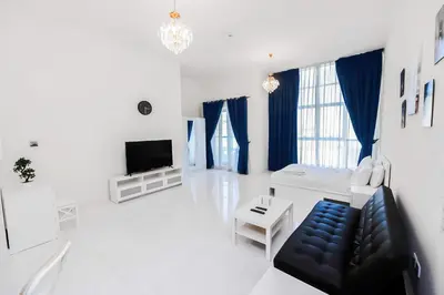 a white living room with a couch and a tv at MK Residence JVC in Dubai