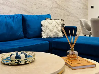 a blue couch in a living room with a table at Peaceful 2 Bed Oasis Suite in JVC in Dubai