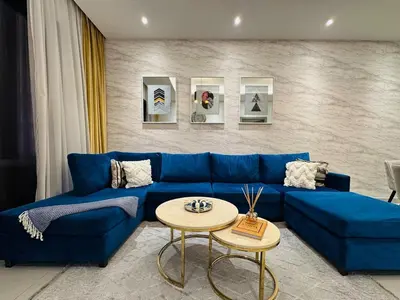 a living room with a blue couch and a table at Peaceful 2 Bed Oasis Suite in JVC in Dubai