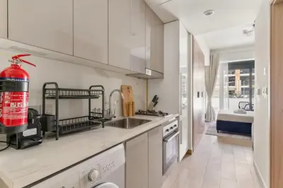 a white kitchen with a sink and a stove at Stunning Luxury Studio in Dubai in Dubai