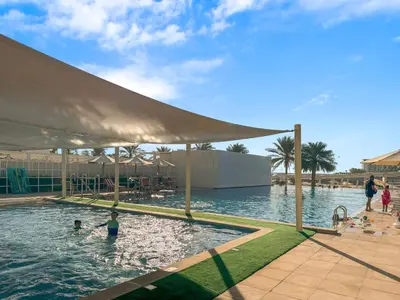 a swimming pool with two children in the water at Serene 2-bedroom Escape with Sea Steps Away in JBR in Dubai