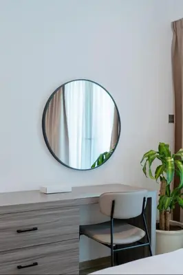 a mirror on a wall above a desk with a chair at AWS Holiday Homes - Style in Downtown in Dubai