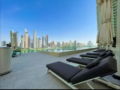 a row of chaise lounges on a rooftop with a city skyline at AWS Holiday Homes - Amazing Beachfront Stay in Dubai