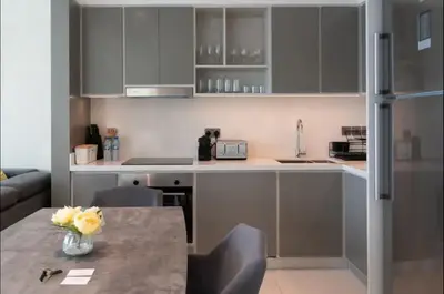 a kitchen with gray cabinets and a table with flowers on it at AWS Holiday Homes - Amazing Beachfront Stay in Dubai