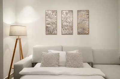 a living room with a couch and three paintings on the wall at FIRST CLASS 1BR Modern Luxury on High Floor in Dubai