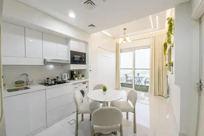 a kitchen with a white table and chairs and a table and a counter at Designer 1BR I Golf View I Comfortably Sleeps 4 in Dubai