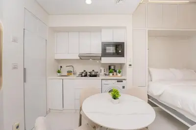 a white kitchen with a white table and a bed at Designer 1BR I Golf View I Comfortably Sleeps 4 in Dubai