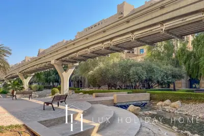 a bridge over a park with benches and trees at LUX The Palm Island Shoreline Suite in Dubai