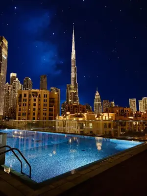 a large swimming pool with a city skyline at night at FULL Burj Khalifa View Luxury Stay in Downtown in Dubai