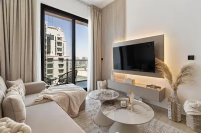a living room with a tv and a large window at Modern 1BR Apartment - JVC - WiFi - Pool - Gym in Dubai