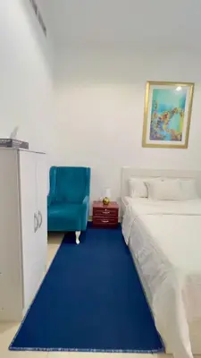 a bedroom with a bed and a blue chair at Amiqa Homes DIP 1 in Dubai