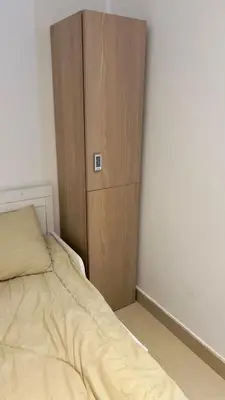 a bedroom with a bed and a wooden cabinet at Amiqa Homes DIP 1 in Dubai