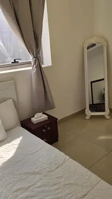 a bedroom with a bed and a mirror and a window at Amiqa Homes DIP 1 in Dubai