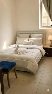 a bedroom with a large white bed with a blue stool at Amiqa Homes DIP 1 in Dubai