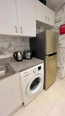 a kitchen with a washing machine and a refrigerator at Amiqa Homes DIP 1 in Dubai