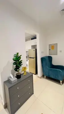 a living room with a blue chair and a dresser at Amiqa Homes DIP 1 in Dubai