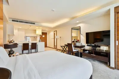 a bedroom with a white bed and a kitchen at Luxurious Studio with Burj Khalifa View Direct Dubai Mall Access - Kempinski Residence in Dubai