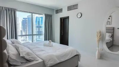 a white bedroom with a large bed and a mirror at Sky High 2BR Stay Amazing Marina Views Near Metro & Mall in Dubai