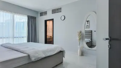 a white bedroom with a bed and a mirror at Sky High 2BR Stay Amazing Marina Views Near Metro & Mall in Dubai