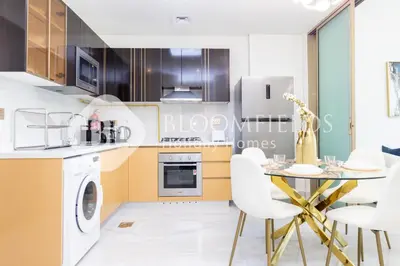 a kitchen with a table and white chairs at Bloomfields Hidden Gem 1Br with Private Pool in Dubai