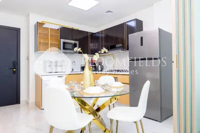 a kitchen with a table and white chairs and a refrigerator at Bloomfields Hidden Gem 1Br with Private Pool in Dubai