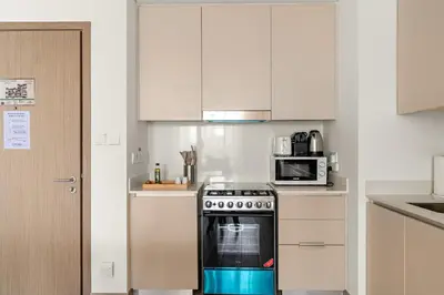 a kitchen with a stove and a microwave at Silkhaus Chic 1BR in Creek Beach Grove with Pool view in Dubai
