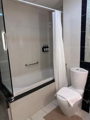 a bathroom with a tub and a toilet and a shower at Cozy 1BR, 2Min to Dubai Mall in Dubai