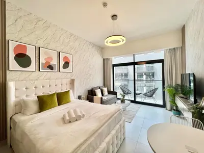 a bedroom with a large white bed and a table at Stylish Stay in the Heart of JVC in Dubai