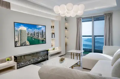 a living room with a white couch and a tv at 49 -Elegant Princess Tower Family Apartment with Palm View, Balcony & Pool in Dubai