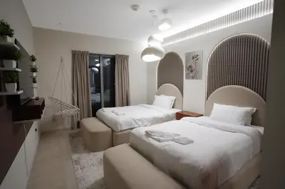 a bedroom with two beds and a chair in it at 49 -Elegant Princess Tower Family Apartment with Palm View, Balcony & Pool in Dubai