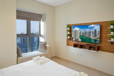 a bedroom with a tv on the wall at 49 -Elegant Princess Tower Family Apartment with Palm View, Balcony & Pool in Dubai