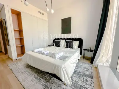 a bedroom with a bed with white sheets and a rug at Comfy 1-Bedroom Apartment at Blue Wave - Liwan in Dubai