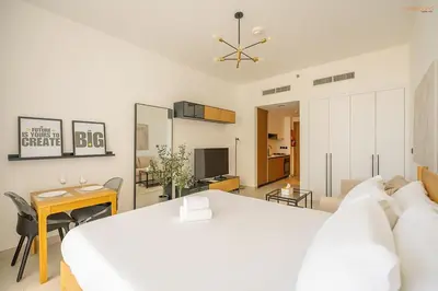a bedroom with a large white bed and a desk at Bnbeyond's Sassy Studio with Expansive Balcony in Dubai