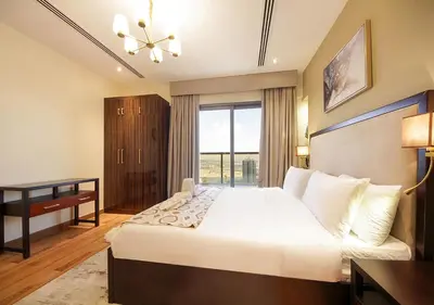 a bedroom with a bed and a desk and a window at Stylish 2BR Downtown Apartment Burj & Mall Nearby in Dubai