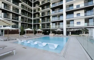 a large swimming pool with white chairs and a building at Peaceful 1br Jvc Pool, Balcony, Parking in Dubai