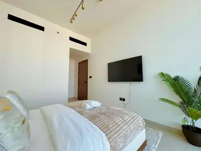 a bedroom with a bed and a tv on the wall at Luxury 2br Private Pool & Balcony Jvc in Dubai