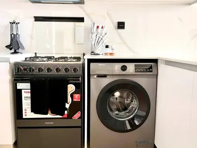 a kitchen with a stove and a washing machine at Jvc 1br Apartment Modern Comfort, Pool, Parking in Dubai