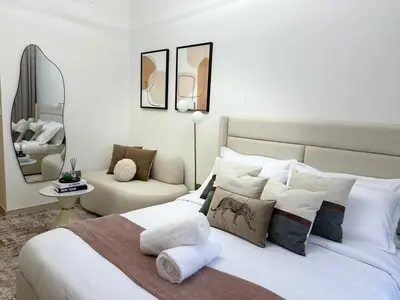 a bedroom with a large white bed and a chair at Luxury studio near Burj Khalifa in Dubai