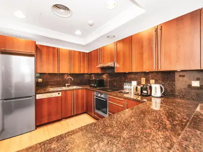 a kitchen with wooden cabinets and stainless steel appliances at New Fairmont Residence with private beach on PalmJumeirah in Dubai