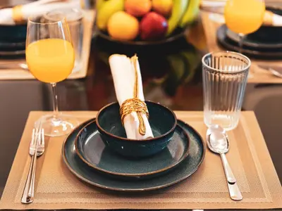 a table with a bowl of food and two glasses of orange juice at New Fairmont Residence with private beach on PalmJumeirah in Dubai
