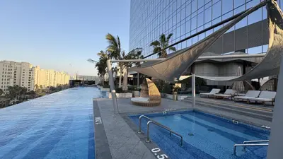 a swimming pool with a hammock next to a building at Ultra-Luxury Studio Palm Tower St. Regis Views High Floor DRP Holiday Homes in Dubai