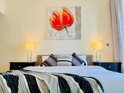 a bedroom with a bed with a red flower painting on the wall at Stylish 1BHK in Marina Steps to Metro & Marina Walk in Dubai